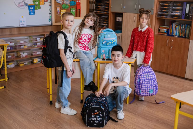 Діти у школі з модними рюкзаками